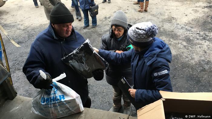 Сотрудники Управления ООН по делам беженцев раздают местному населению теплую одежду