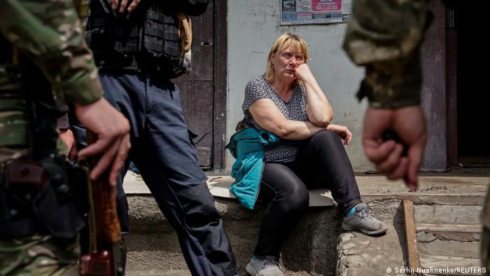Жительница Лисичанска сидит рядом со своей квартирой в окружении сотрудников украинской полиции. Фото 2 июня 2022 года 
