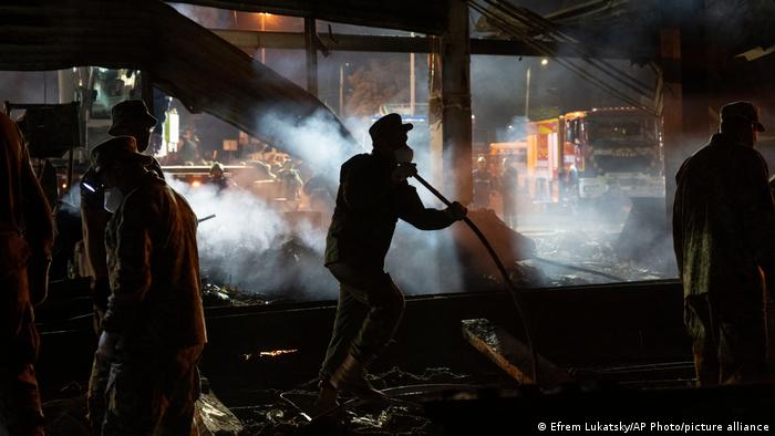 Спасатели и волонтеры тушат огонь в ТЦ Амстор, разрушенном в результате попадания ракеты 27 июня